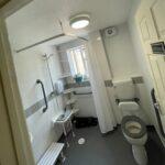Modern accessible bathroom featuring walk-in shower, grab rails, non-slip flooring, and raised toilet — perfect example of bathroom adaptations for disabled individuals.