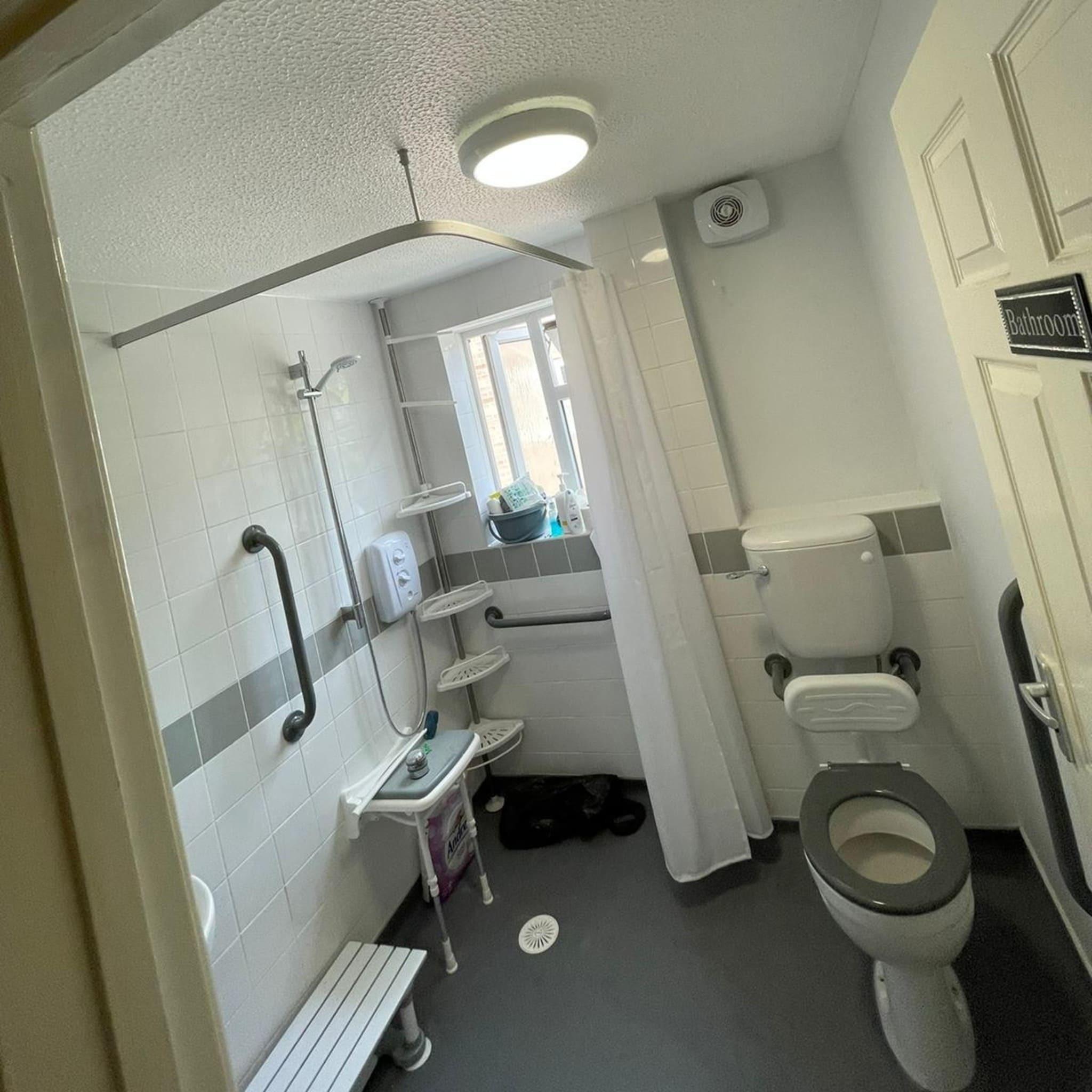 Modern accessible bathroom featuring walk-in shower, grab rails, non-slip flooring, and raised toilet — perfect example of bathroom adaptations for disabled individuals.